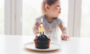 baby sitting with a first birthday cupcake