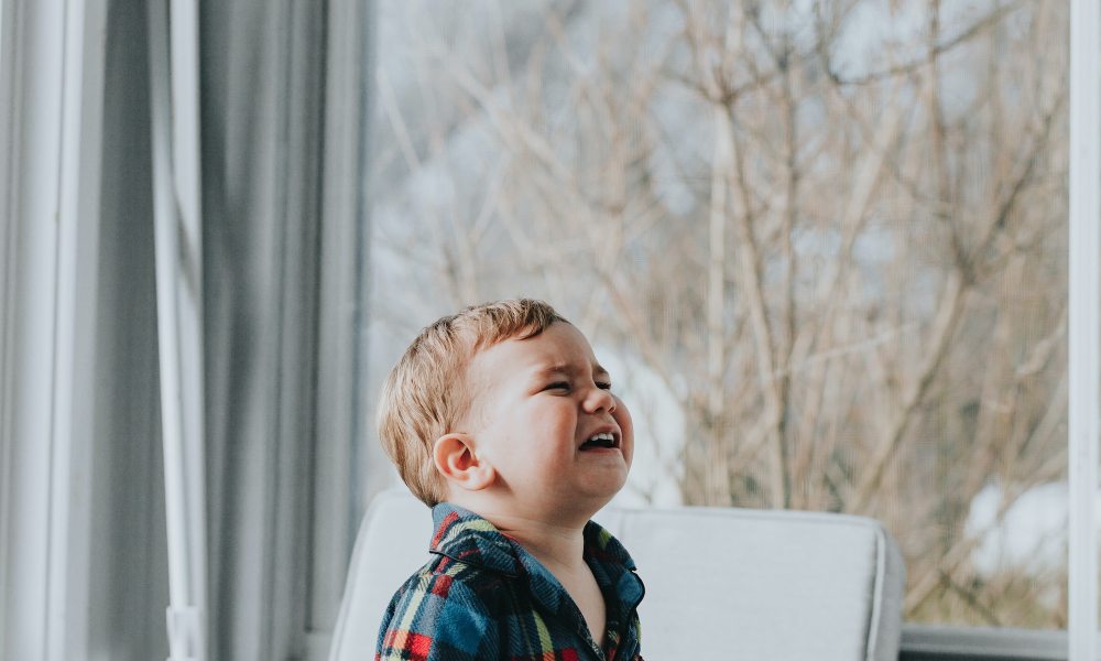 Child crying in a house by a window.