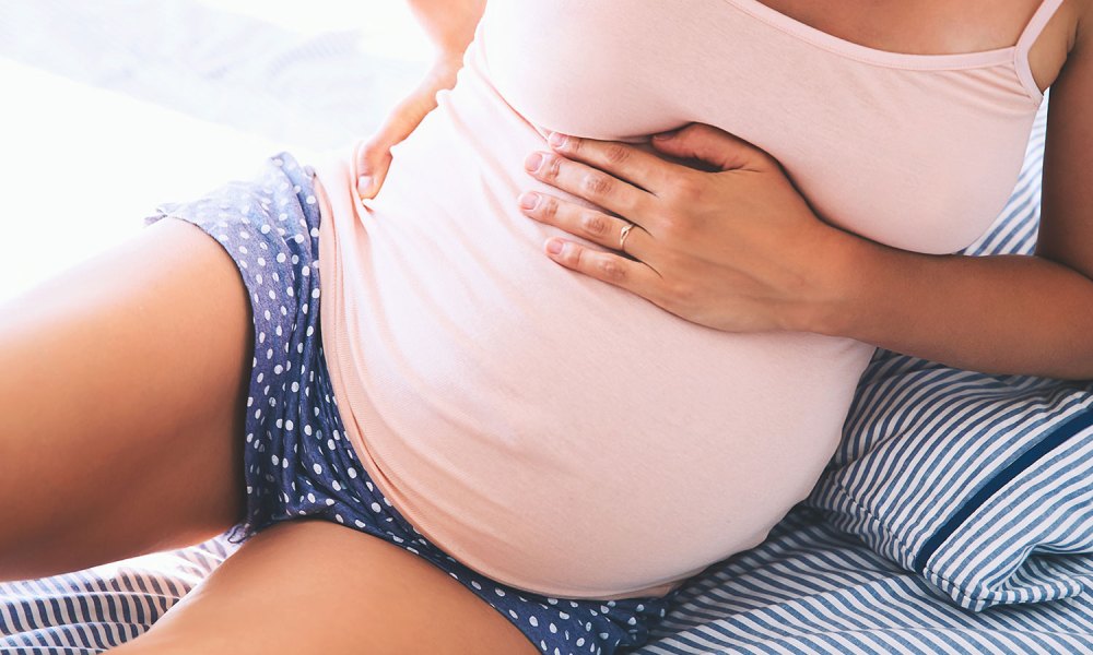 pregnant woman holding her back and belly bump