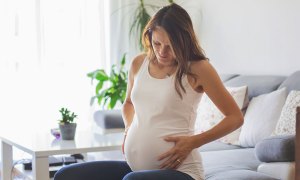 Pregnant woman on couch holding her stomach