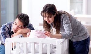 Parents at crib of their sleeping baby.