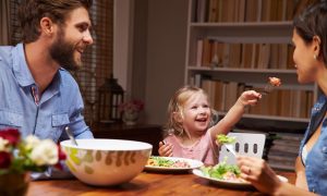 Family of three eating dinner at table at home