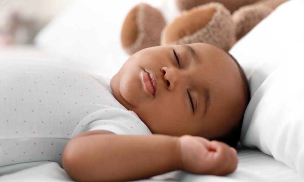 Infant boy sleeping on bed.