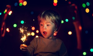 Toddler boy holding a sparkler at a party