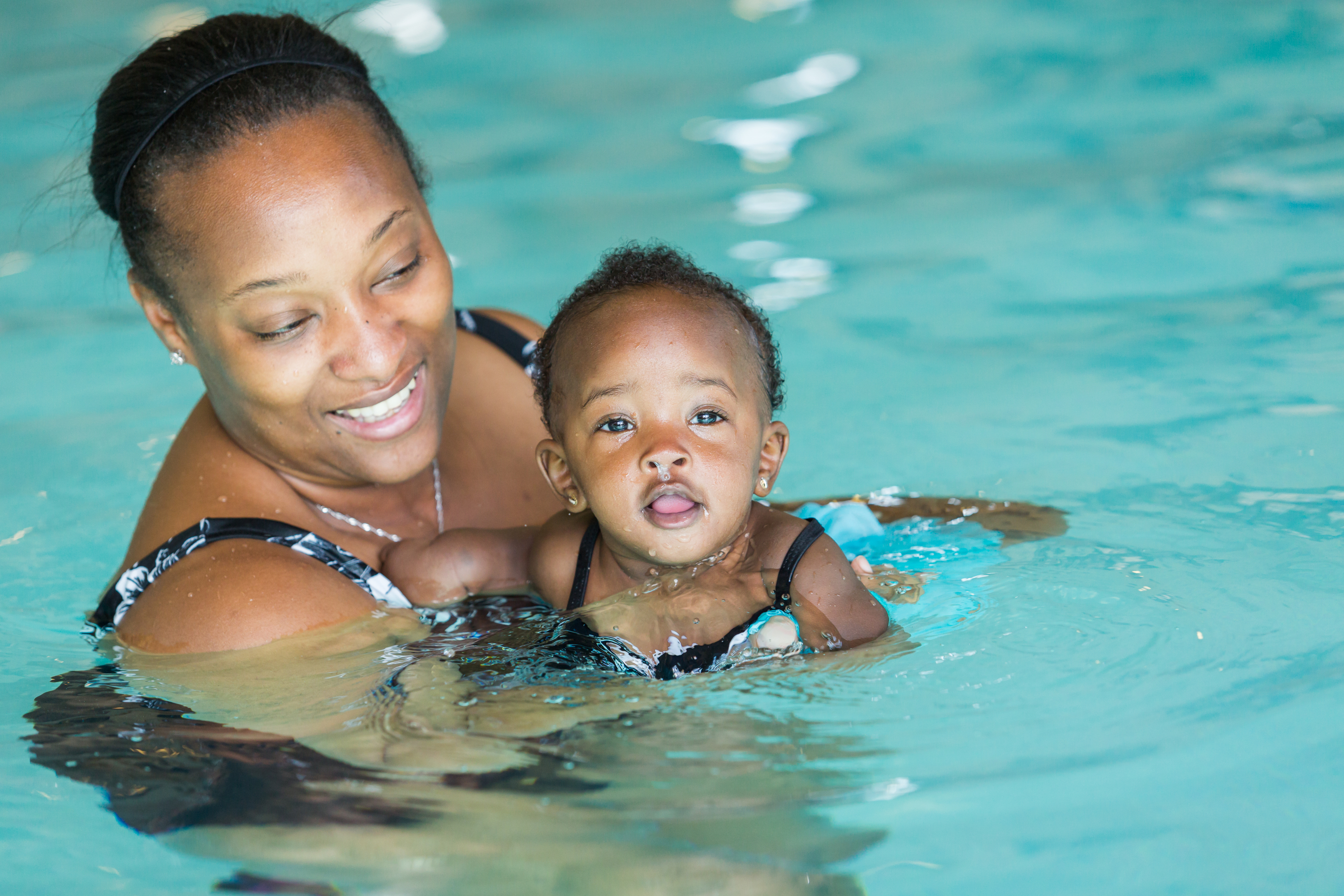 An adult teaching a baby how to swim.
