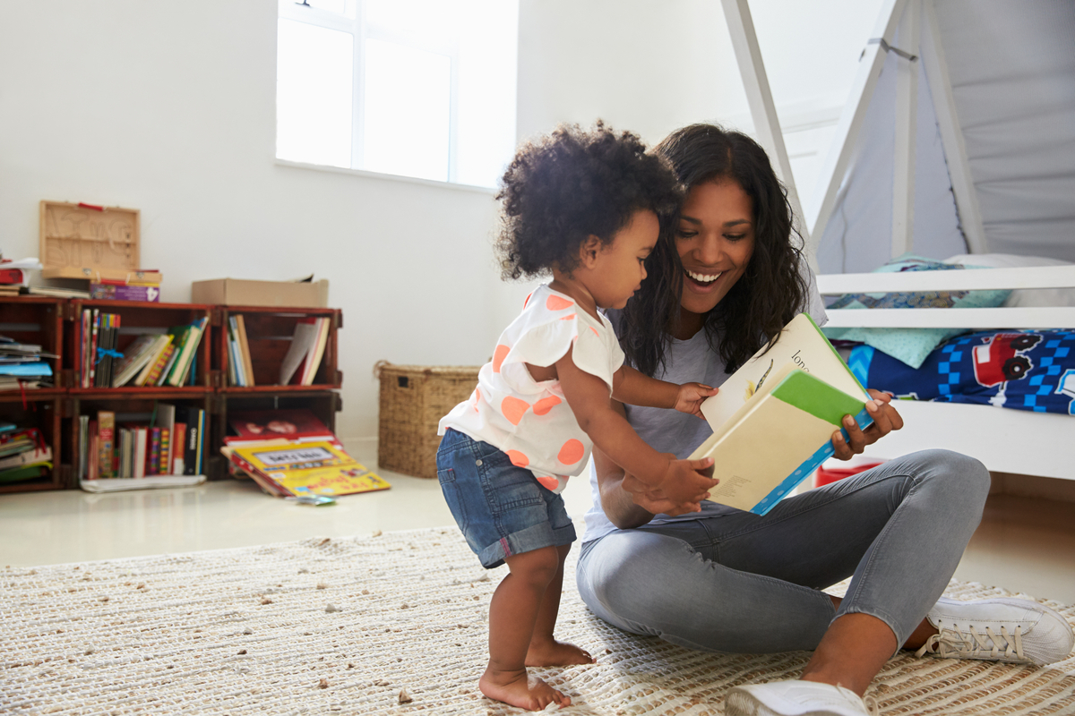 Toddler reading book with mom