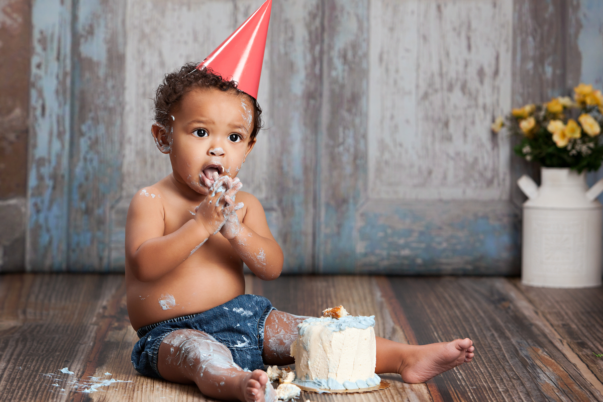 Baby boy enjoying his smash cake on his birthday