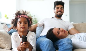 Family of three on a couch watching TV