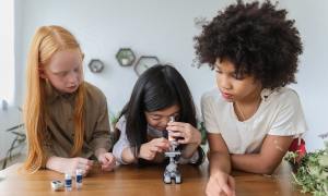 Three young girls using a microscope