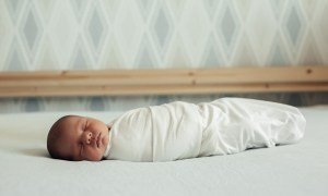 Swaddled sleeping baby in a bed.