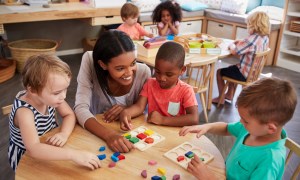 Preschool teacher talking with students at a table.