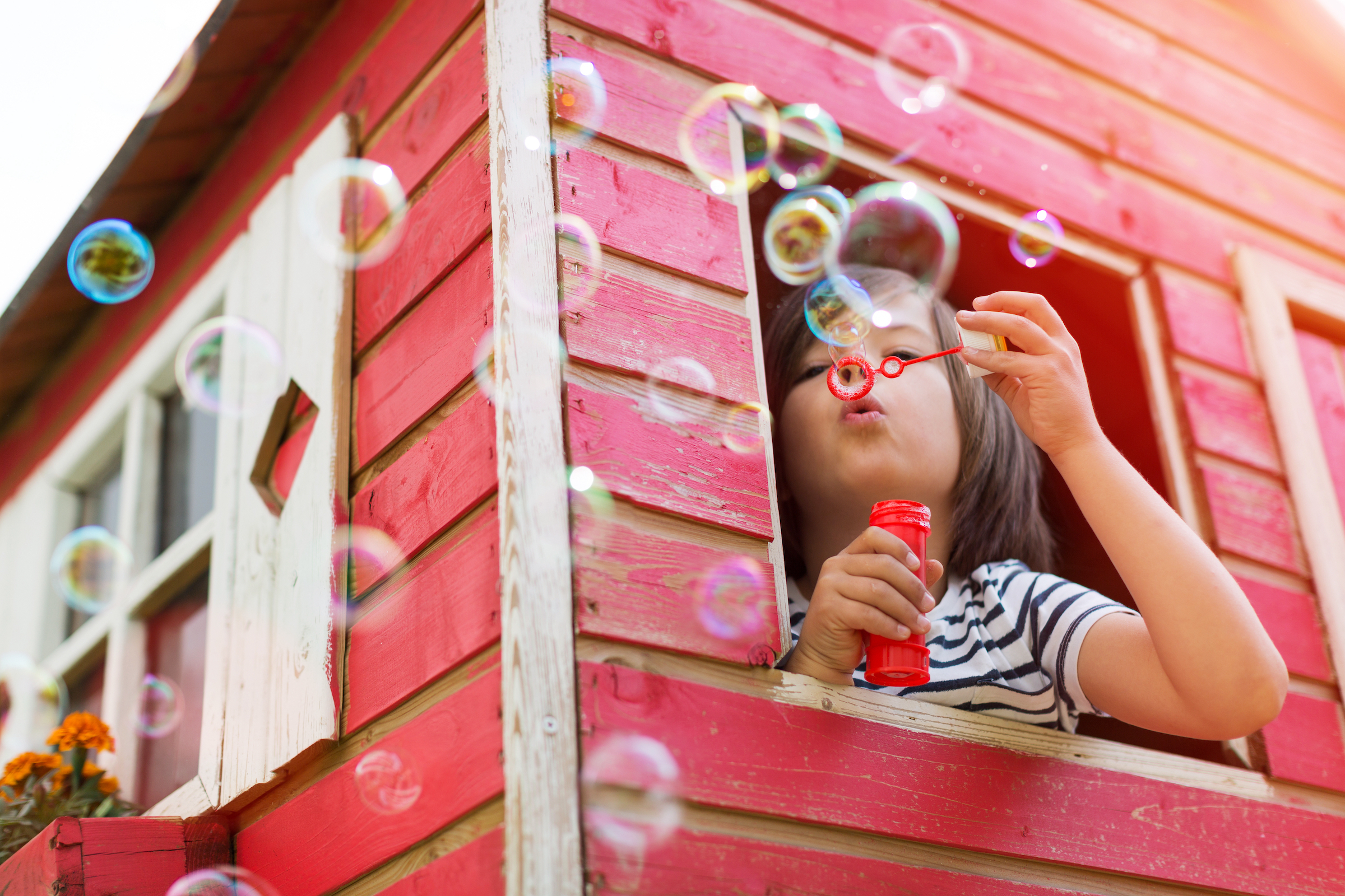 Child blowing bubbles in a playhouse