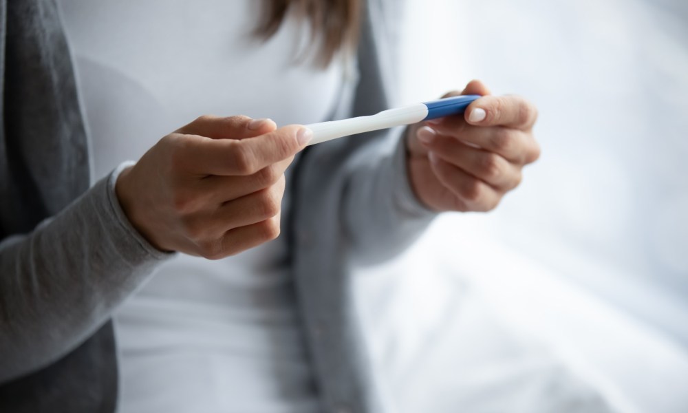 Woman holding a pregnancy test.