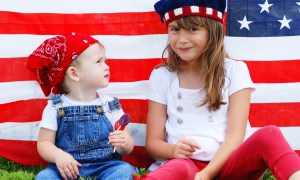 Two kids sitting in front of a U.S. flag