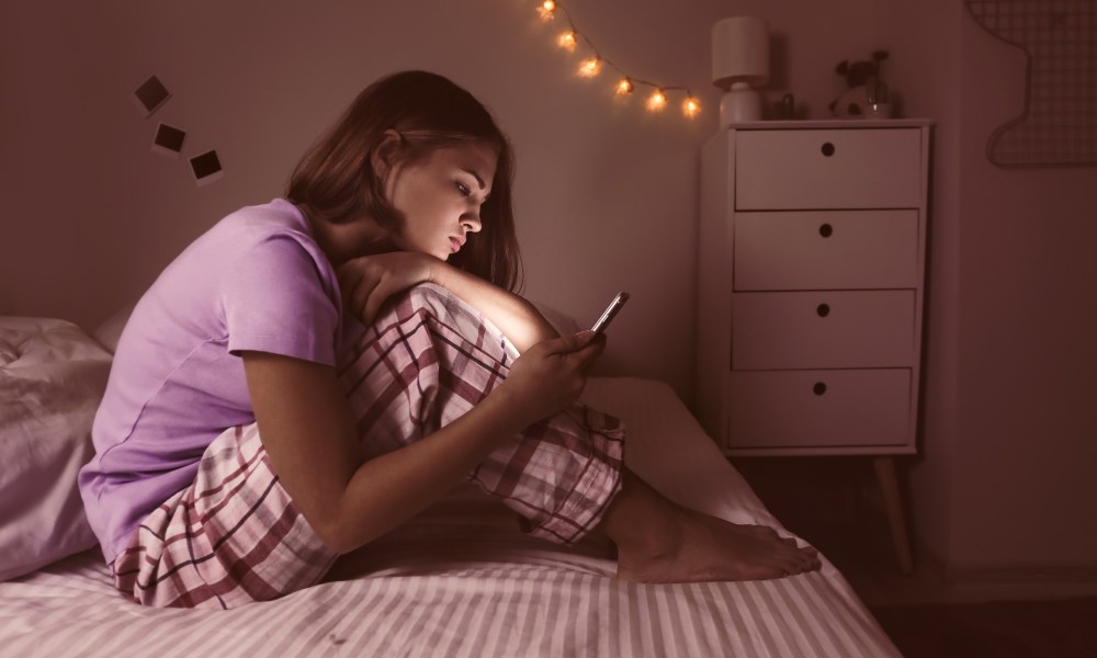 A teenage girl by herself on her cell phone.