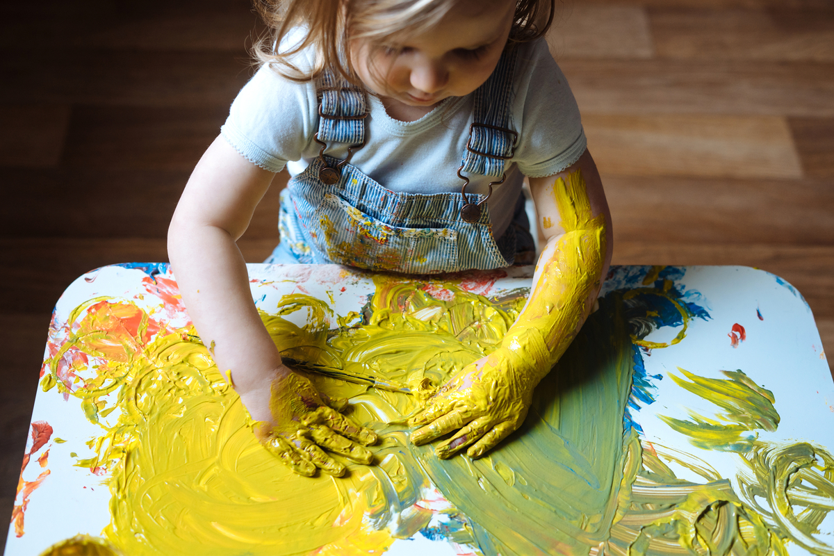 toddler girl having fun finger painting