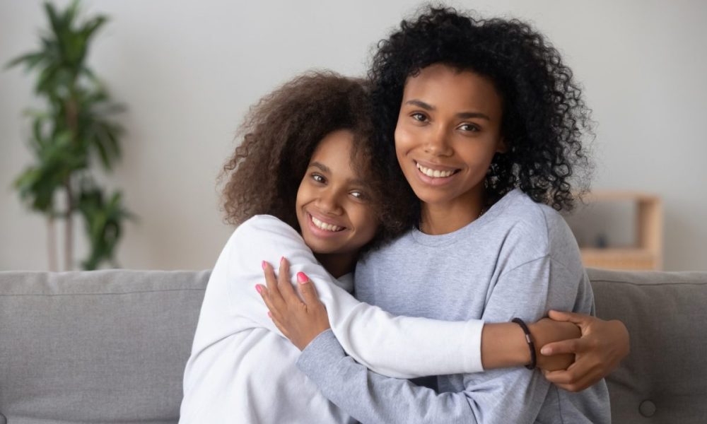 A teen hugging their parent where both are smiling