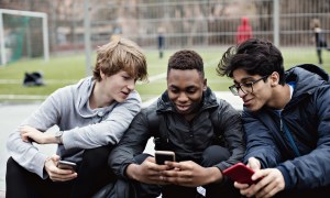 Three teen boys looking at phones.