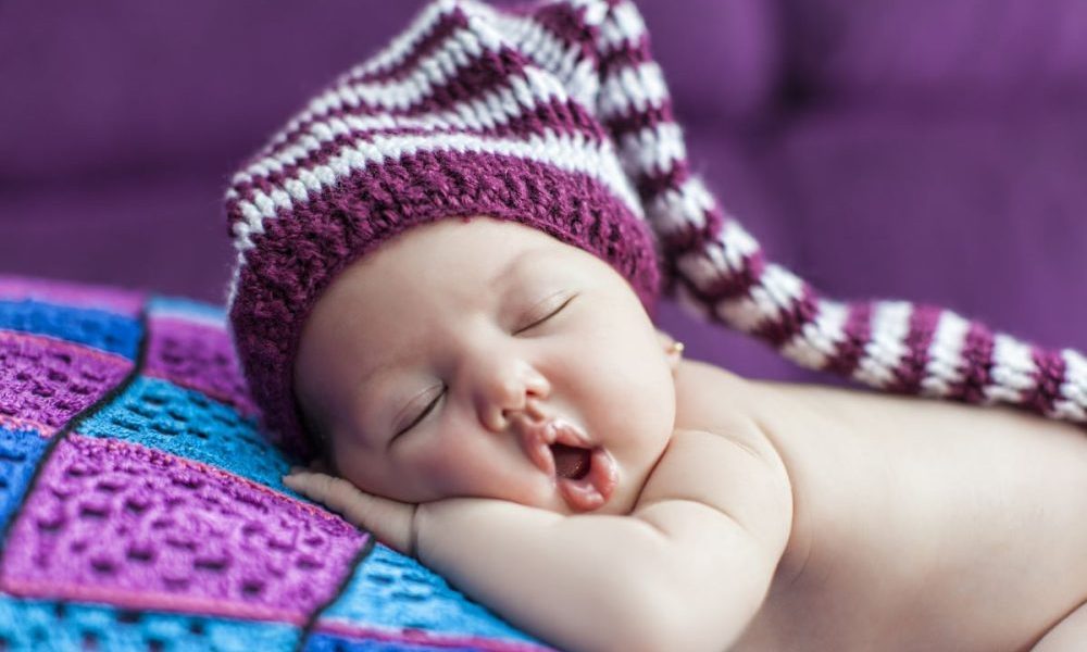 Cute newborn baby sleeps in a hat.