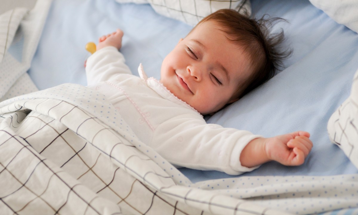 Baby sleeping on his back and smiling.