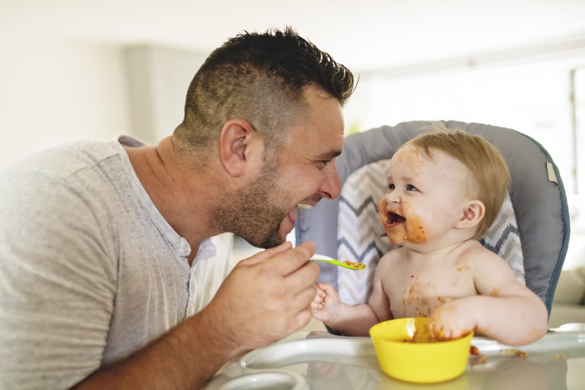 A parent feeding their baby some baby food.