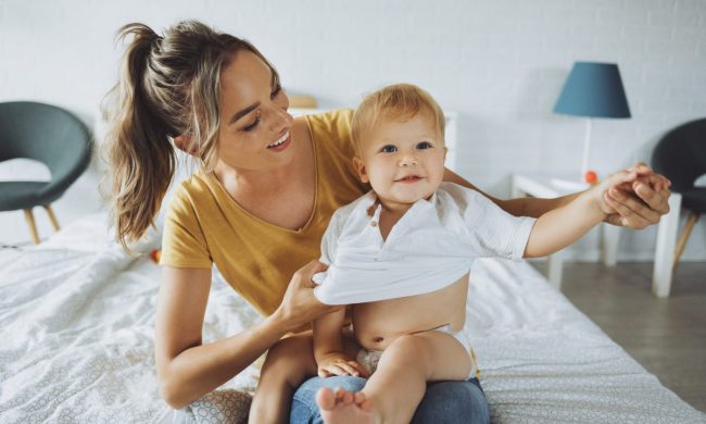 A parent dressing their baby