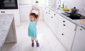 Little girl about to throw a bowl on the kitchen floor.