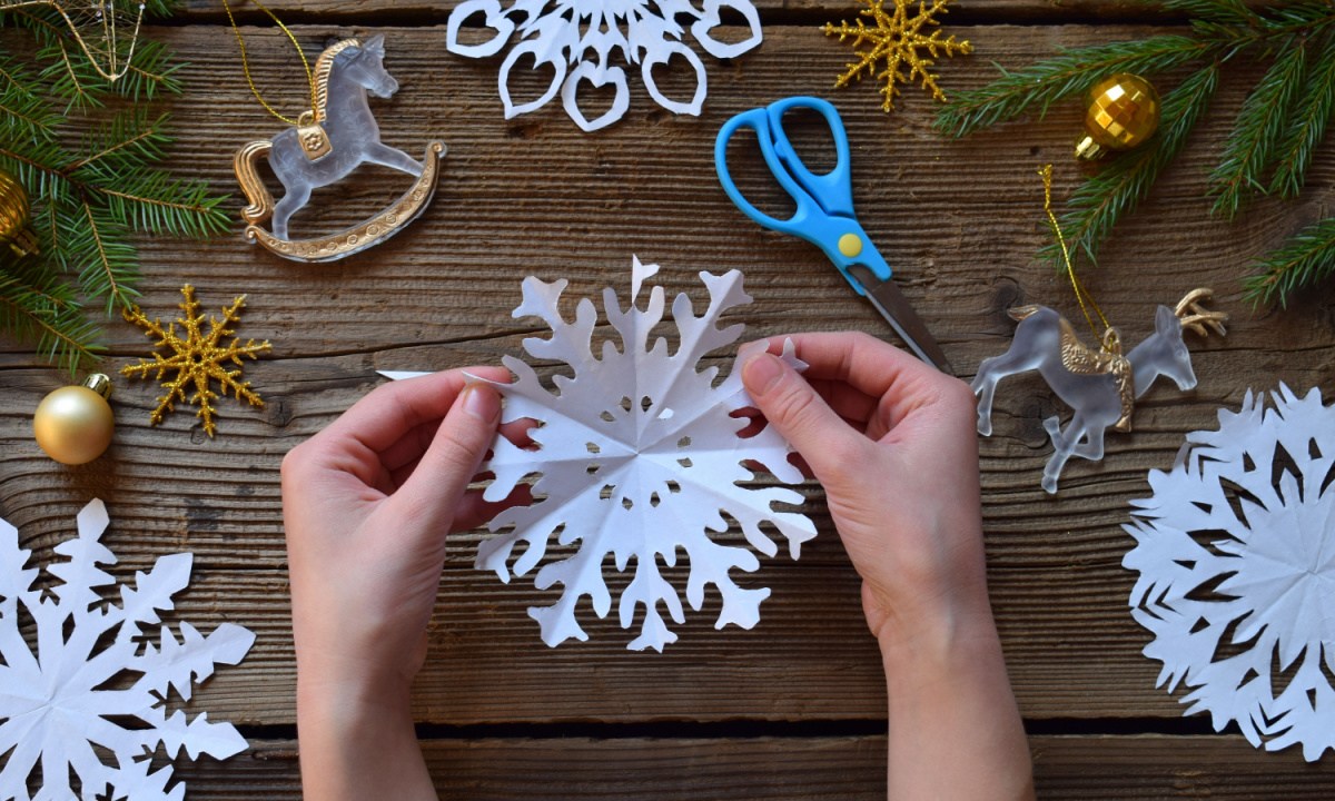 Hands creating paper snowflakes