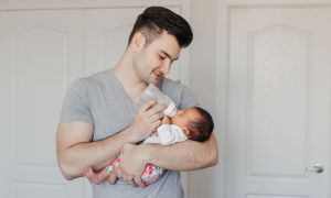 Dad feeding his newborn with a bottle.