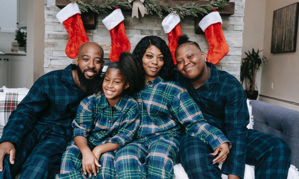 A family in pajamas in front of Christmas decorations