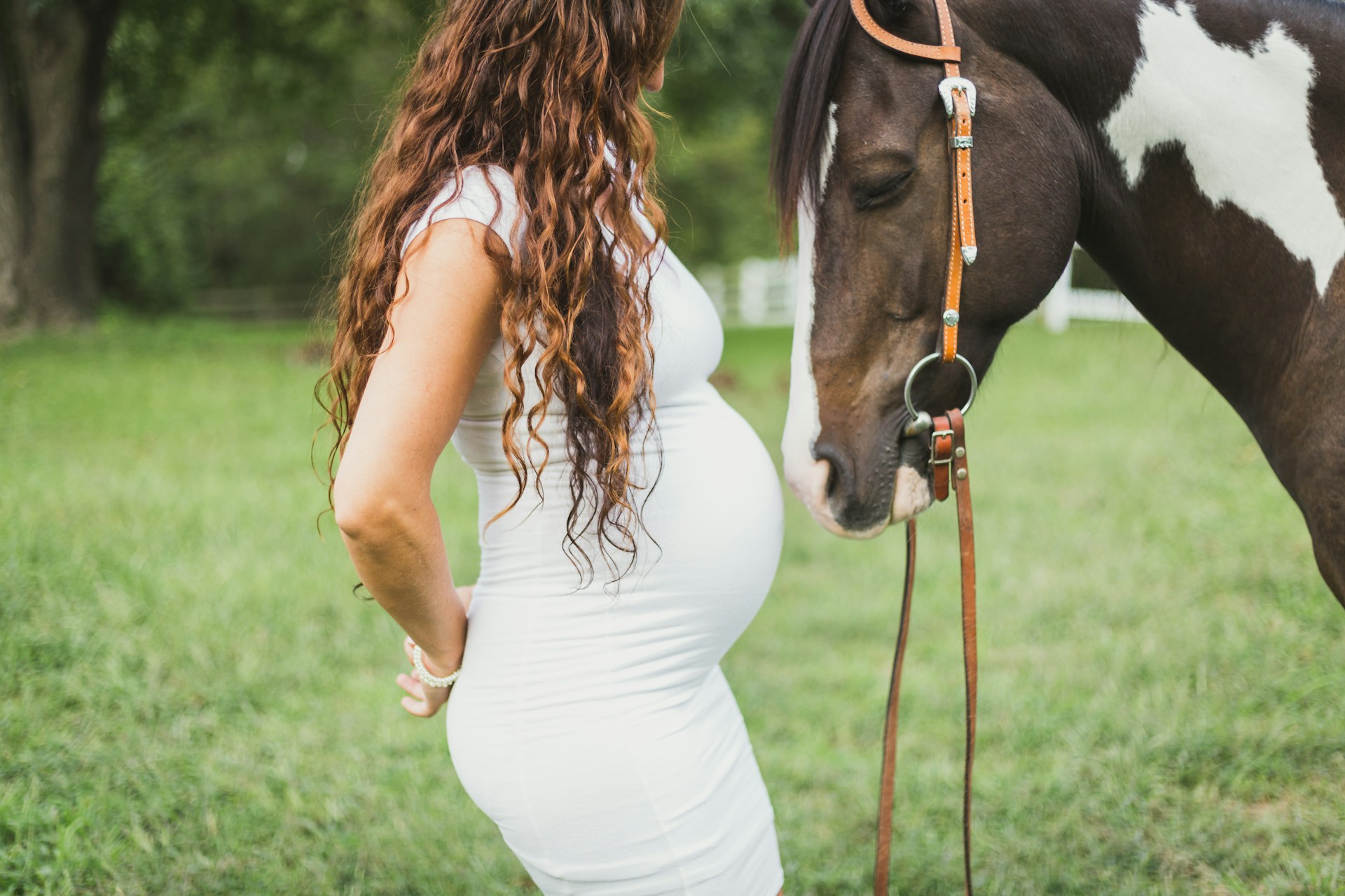 Pregnant woman standing next to a horse