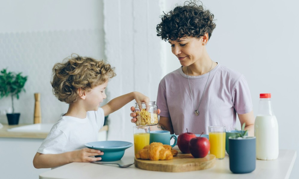 A parent helping a child add toppings to their breakfast