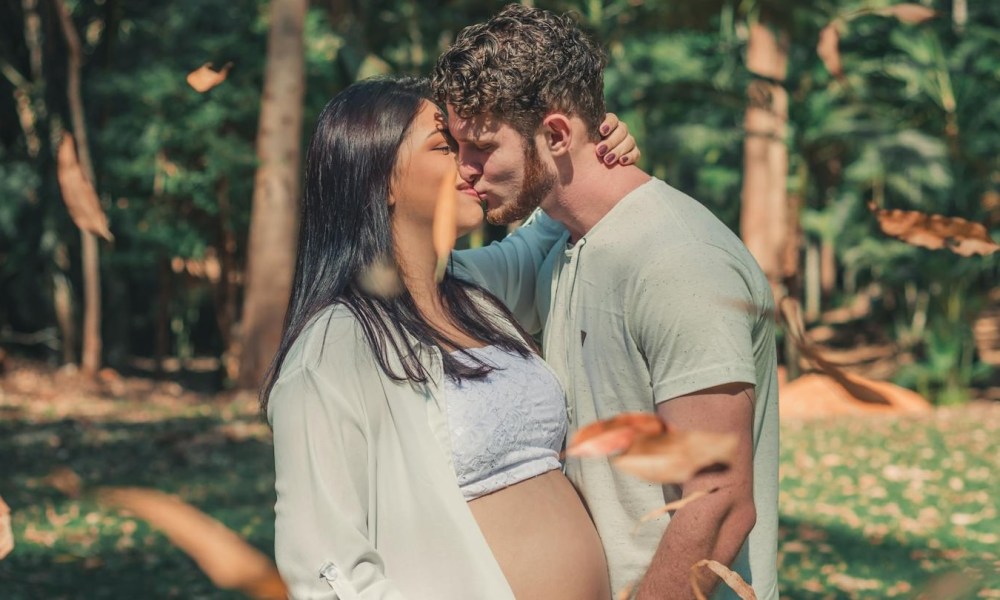 a couple kissing woman is pregnant