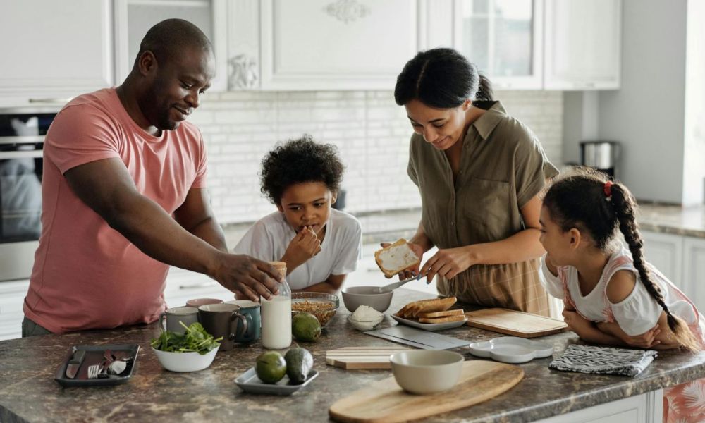 Parents and kids having fun in the kitchen making breakfast