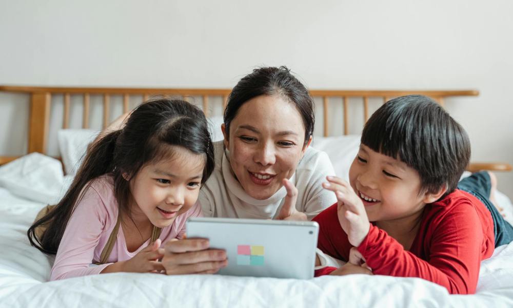 Children looking at a tablet screen with their parent