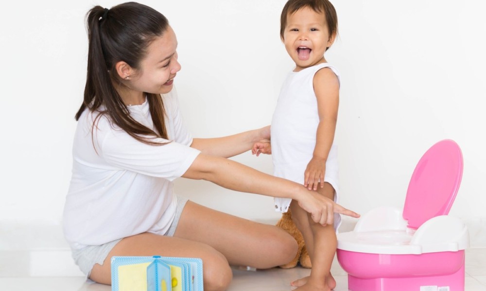 A mother helping her toddler on the potty